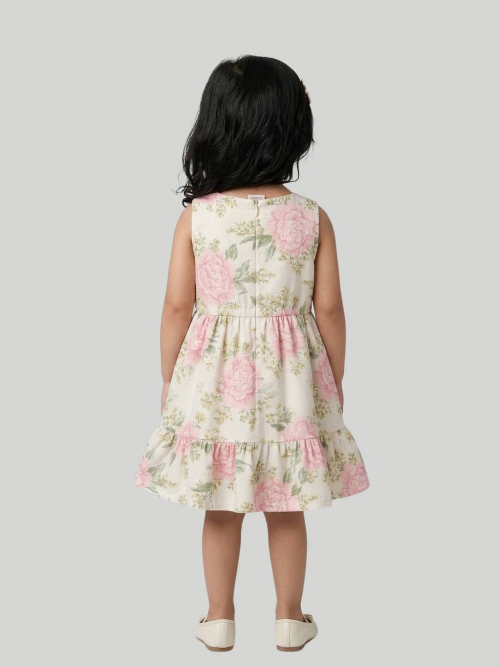 Cream floral sleeveless dress with soft ruffle hem detail.