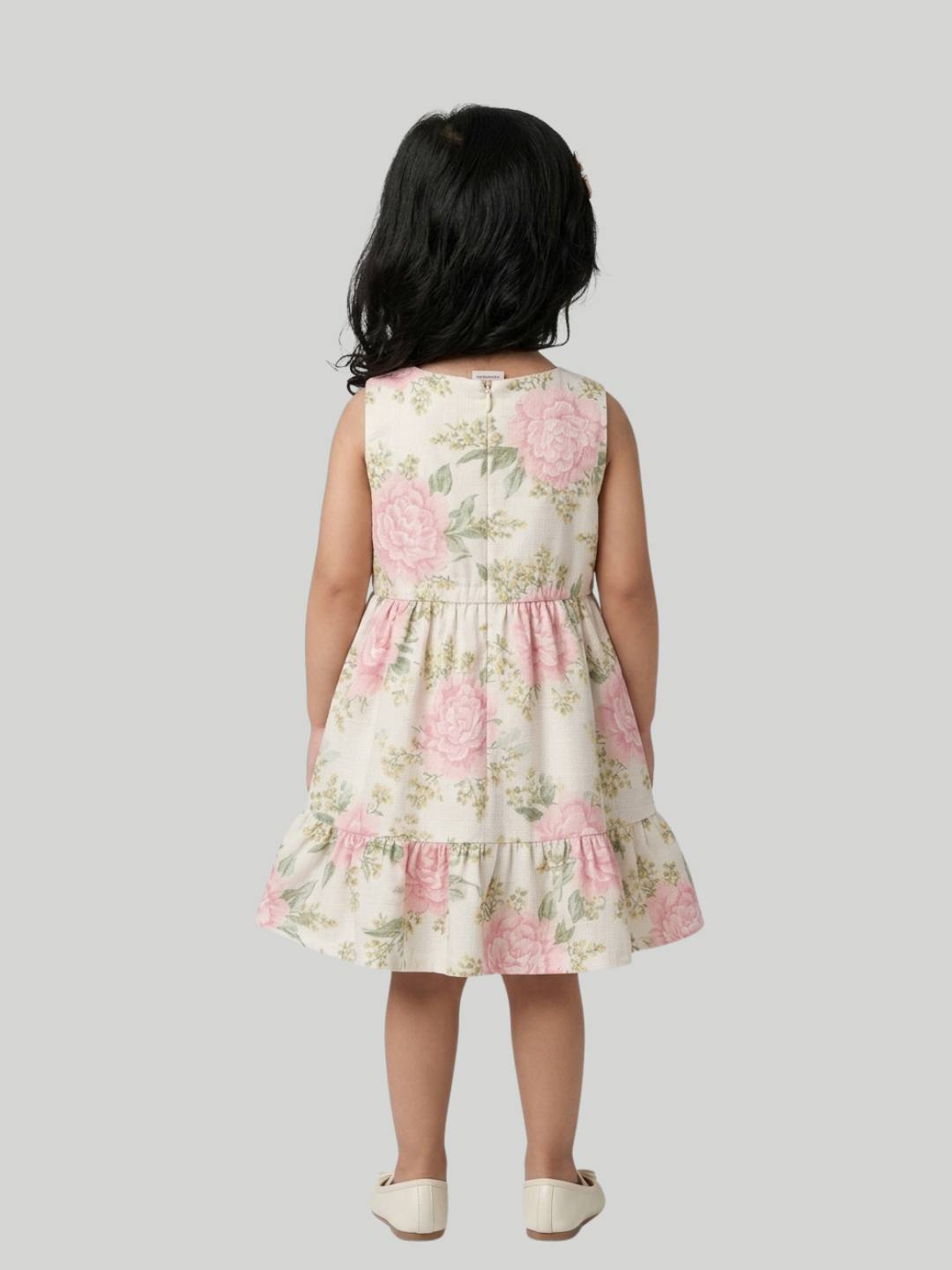 Cream floral sleeveless dress with soft ruffle hem detail.