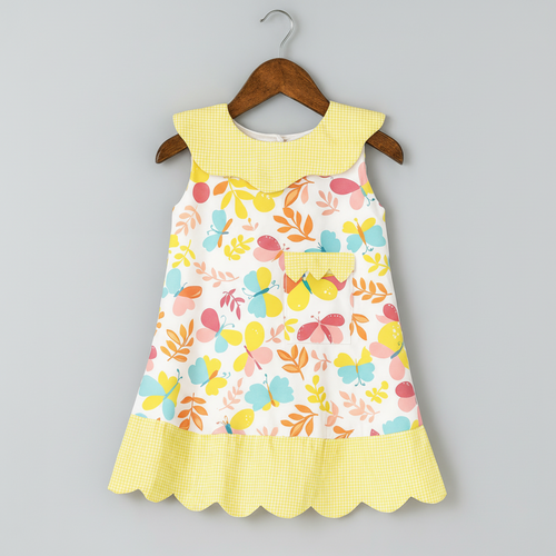 Colorful children's dress with floral pattern and yellow accents on a hanger against a gray background